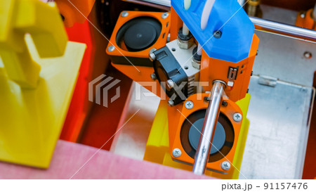 Handmade orange 3D printer machine printing plastic model - close up top view Handmade orange 3D printer machine printing plastic model - close up top view 91157476