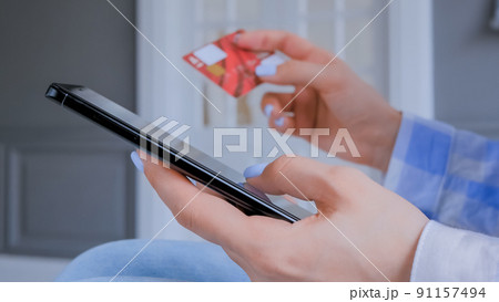 Woman using smartphone and credit card for online shopping - close up side view Woman using smartphone and credit card for online shopping - close up side view 91157494