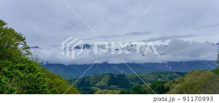 峠の展望台から見た低く雲の垂れ込めた残雪のアルプスの山並みのパノラマ情景@長野 峠の展望台から見た低く雲の垂れ込めた残雪のアルプスの山並みのパノラマ情景@長野 91170993