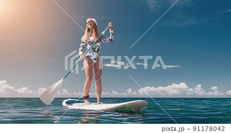Healthy happy fit woman in bikini relaxing on a sup surfboard, floating on the clear turquoise sea water. Recreational Sports. Stand Up Paddle boarding. Summer fun, holidays travel. Active lifestyle 91178042