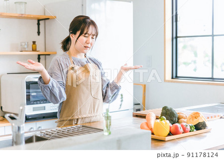 キッチンにいる料理が苦手なエプロン姿の女性（お手上げ） 91178124