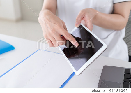病院で働く女性がタブレットを操作、説明している 病院で働く女性がタブレットを操作、説明している 91181092