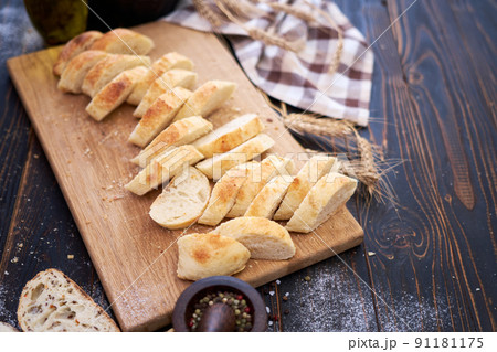 Fresh sliced bread on wooden cutting board at kitchen table Fresh sliced bread on wooden cutting board at kitchen table 91181175