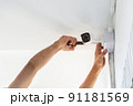 Technicians using a screwdriver to install  the CCTV cameras. 91181569