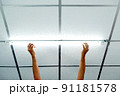 Installing a long LED light bulb on the ceiling. 91181578