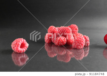 raspberries lie in a heap on a black background with a reflection. Vitamins seasonal berries freshness taste benefit. Raspberries for packaging labels 91184748