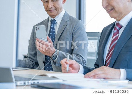 オフィスでスマホを使うシニア男性の手元のアップ 91186086