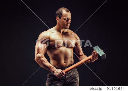 Muscular man with great anatomy posing on a black background with a big hummer in his hands 91191644