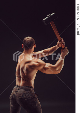 Back view of a muscular man with great anatomy posing on a black background with a big hummer in his hands Back view of a muscular man with great anatomy posing on a black background with a big hummer in his hands 91191663