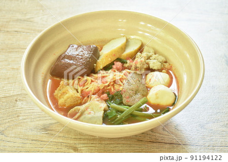 Chinese yellow egg noodles with fish ball and chop pork in spicy red tom yum soup on bowl Chinese yellow egg noodles with fish ball and chop pork in spicy red tom yum soup on bowl 91194122