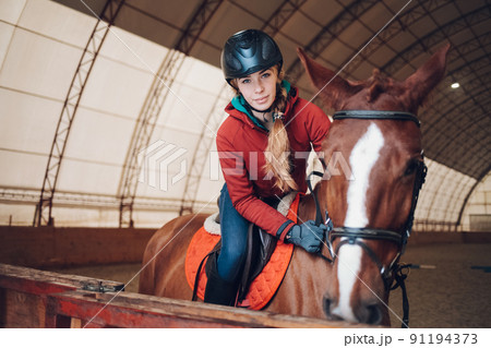 Pretty young woman riding a horse in the arena for equestrian sport. Pretty young woman riding a horse in the arena for equestrian sport. 91194373