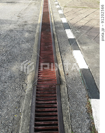 water drain or ditch on the road. Gutters drain grate, drain cover. Road drains - sewer cover. iron grate of water drain on the road in every city. Water go down to the drain on the road 91202566
