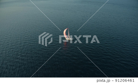 Aerial shot of a moving sailing yacht with pink sail on the sea 91206461