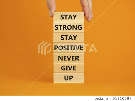 Never give up symbol. Wooden blocks with concept words Stay strong stay positive never give up. Beautiful orange background. Copy space. Businessman hand. Motivational business never give up concept. 91210297