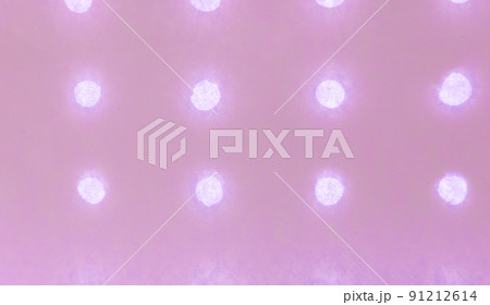 Pink abstract paper background with small round holes arranged in a row and glowing against the light background Pink abstract paper background with small round holes arranged in a row and glowing against the light background 91212614