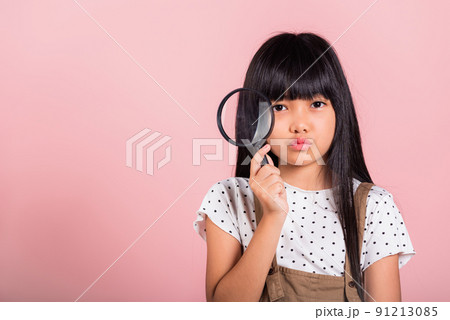 Asian little kid 10 years old funny looking through magnifying glass 91213085