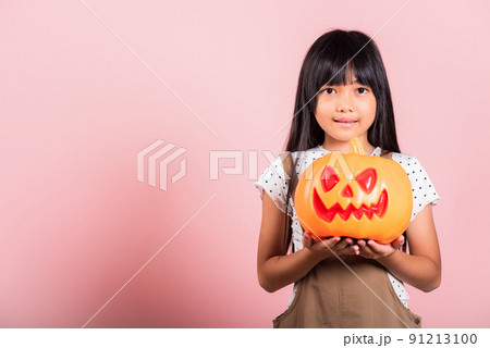 Asian little kid 10 years old holding carved Halloween pumpkin 91213100