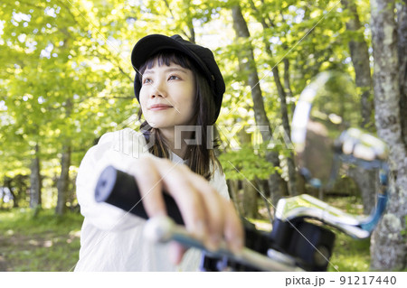 バイク女子イメージ　森でバイクにまたがる若い女性 91217440