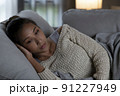 Frustrated and depressed young Asian woman is crying while lying in the couch at home 91227949