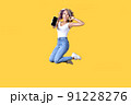 Full length portrait of young Asian woman holding smartphone jumping on yellow background 91228276