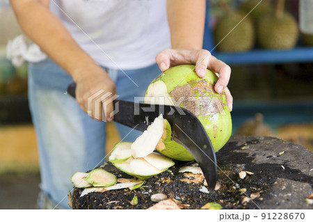 Woman cutting fresh coconut at the market 91228670