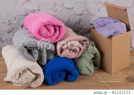 e-commerce concept, a large assortment of wool sweaters, one sweater is packed in a cardboard box 91231171