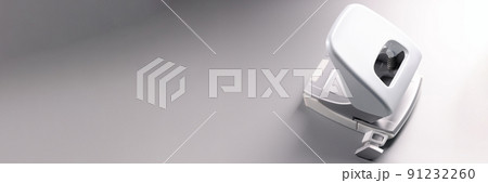 Closeup of white hole punch on gray background 91232260