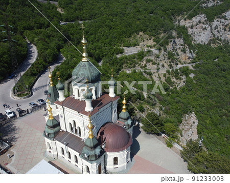 Aerial View of Foros Church and Mount road through the spring forest. Popular tourist attraction near Yalta in the Crimea. Top view Church of Holy Resurrection of Christ on Red cliff over Foros Aerial View of Foros Church and Mount road through the spring forest. Popular tourist attraction near Yalta in the Crimea. Top view Church of Holy Resurrection of Christ on Red cliff over Foros 91233003