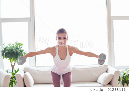 Active woman doing fitness exercises with dumbbells at home. Sport and recreation concept. Active woman doing fitness exercises with dumbbells at home. Sport and recreation concept. 91233111