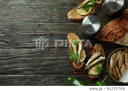 Concept of tasty snack with sandwiches with sprats on wooden background Concept of tasty snack with sandwiches with sprats on wooden background 91235709