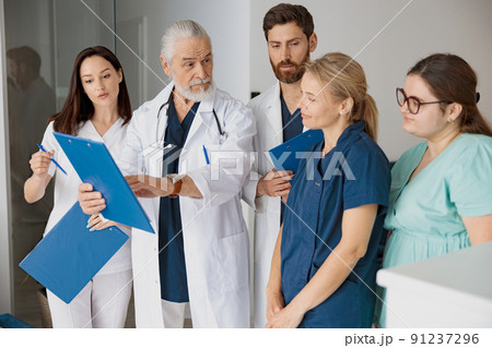 Doctor giving lecture to interns in hospital discussing patient diagnosis 91237296