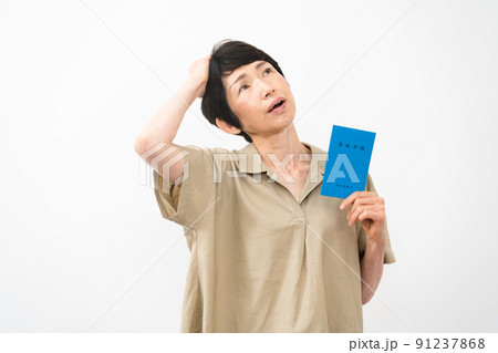年金手帳を持ちながら不安な表情をするミドル女性 年金手帳を持ちながら不安な表情をするミドル女性 91237868