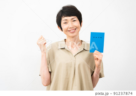 年金手帳を持ってガッツポーズをするミドル女性 年金手帳を持ってガッツポーズをするミドル女性 91237874