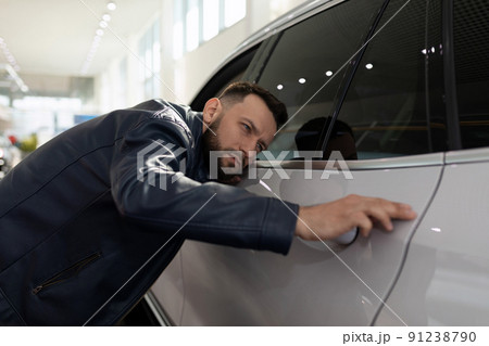 young man in a car dealership inspecting a new SUV young man in a car dealership inspecting a new SUV 91238790