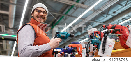 happy customer chooses screwdriver and drill in household goods store happy customer chooses screwdriver and drill in household goods store 91238798