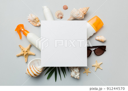 Summer time concept with blank greeting card and blank white paper on colored background. Seashells from ocean shore in the shape of frame separated with space for text top view Summer time concept with blank greeting card and blank white paper on colored background. Seashells from ocean shore in the shape of frame separated with space for text top view 91244570