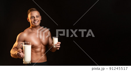 Muscular guy - bodybuilder posing on white background. Athletic man holding a bottle of milk in hand. Sport, health, bodybuilding, strength, power - a concept sports Muscular guy - bodybuilder posing on white background. Athletic man holding a bottle of milk in hand. Sport, health, bodybuilding, strength, power - a concept sports 91245517