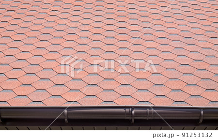 New roof with red shingles. Tiles on the roof of the house. Use to advertise roof fabrication and maintenance. Spotted texture. Affordable roofing. High quality photo with copy space. 91253132
