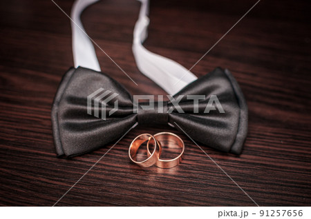 Pair of gold wedding rings and neck tie on the table 91257656