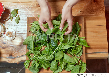 Healthy food concept. Fresh greens. Healthy diet.Female hands on a white background hold green spinach leaves. 91258302