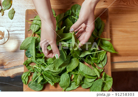 Healthy food concept. Fresh greens. Healthy diet.Female hands on a white background hold green spinach leaves. 91258303