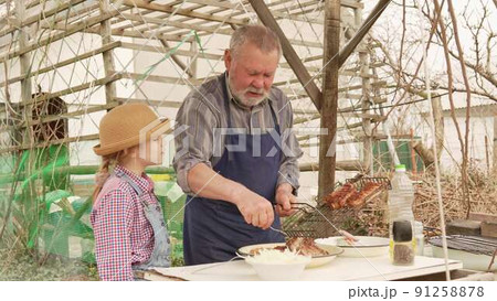 grandfather and granddaughter remove grilled meat, kebab from the grill grate 91258878