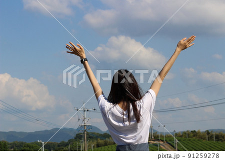 茶畑、山に向かって両手を広げて立っているロングヘアーの女性の後ろ姿 91259278