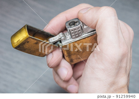handmade golden lighter on a dark background in yellow and blue tones 91259940