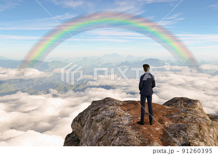 大きな岩がそびえる岸壁にビジネスマンが立つその向こうに虹のアーチが見える。 91260395