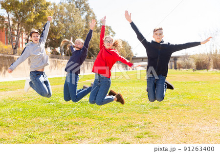 Happy teenagers jumping on the green lawn 91263400