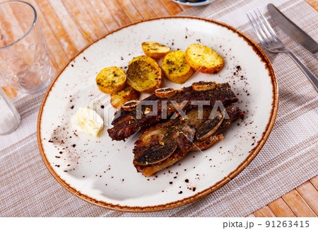 Churrasco grilled veal ribs with baked potatoes and garlic aioli Churrasco grilled veal ribs with baked potatoes and garlic aioli 91263415