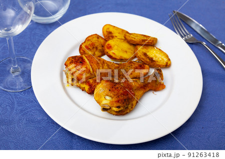 Two chicken drumsticks with baked sliced skinned potatoes Two chicken drumsticks with baked sliced skinned potatoes 91263418