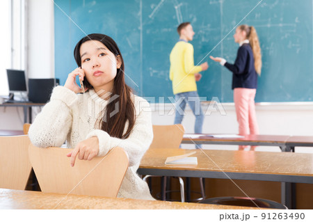 Tired asian student girl talking on phone Tired asian student girl talking on phone 91263490