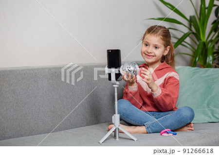 Small blonde blogger girl, an influential person, communicates with subscribers, conducts a live broadcast with a cat, looks at the smartphone screen at home. When taking a selfie, call your friends. 91266618